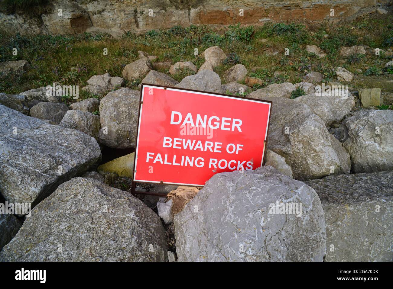 warning sign of falling rocks below cliff at staithes uk Stock Photo