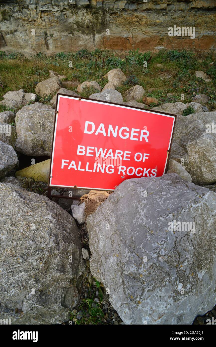 warning sign of falling rocks below cliff at staithes uk Stock Photo