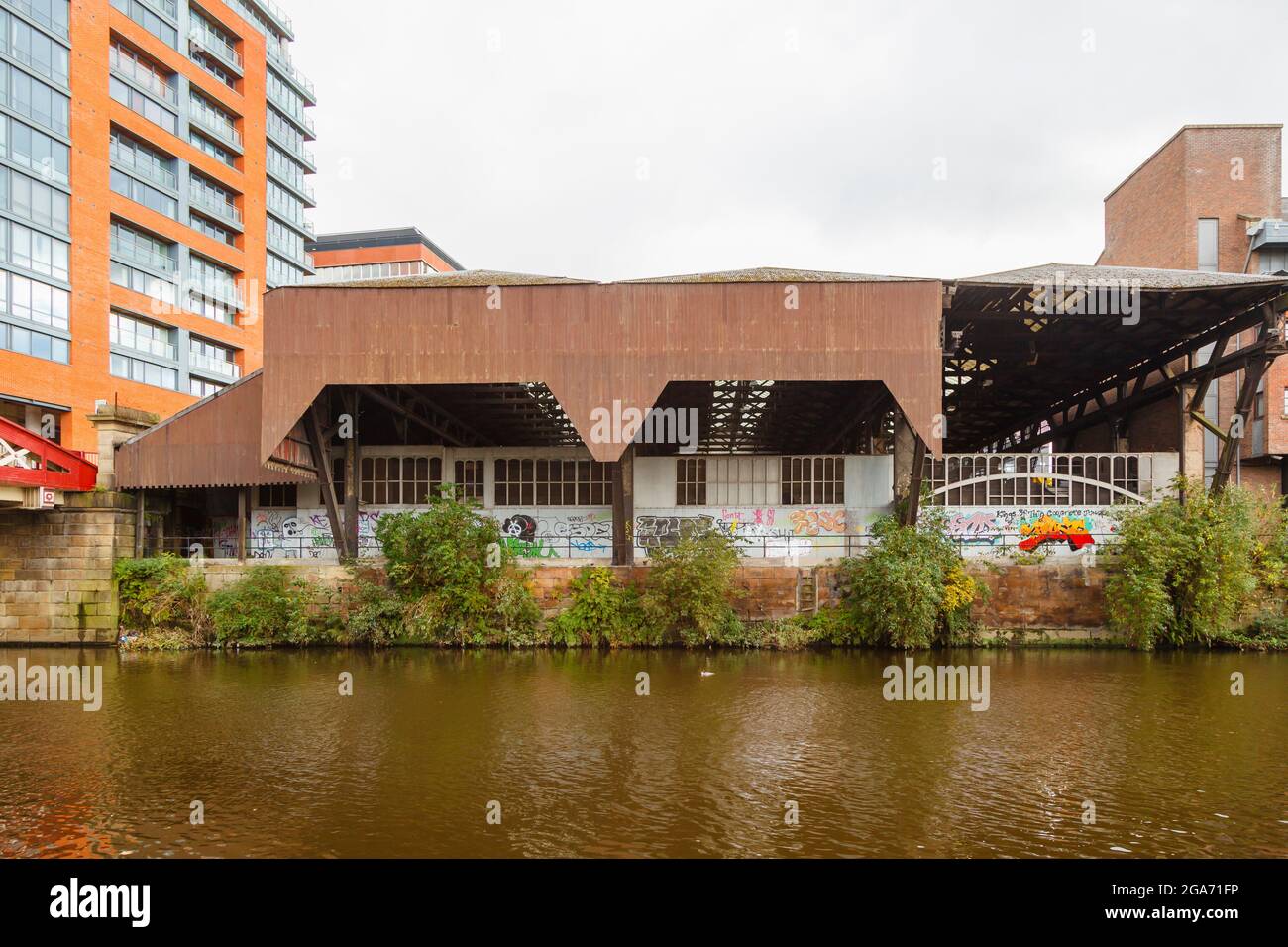 View from the Salford side over the River Irwell of Riverside House, a disused warehouse with graffiti, Spinningfields, Manchester, north-west England Stock Photo