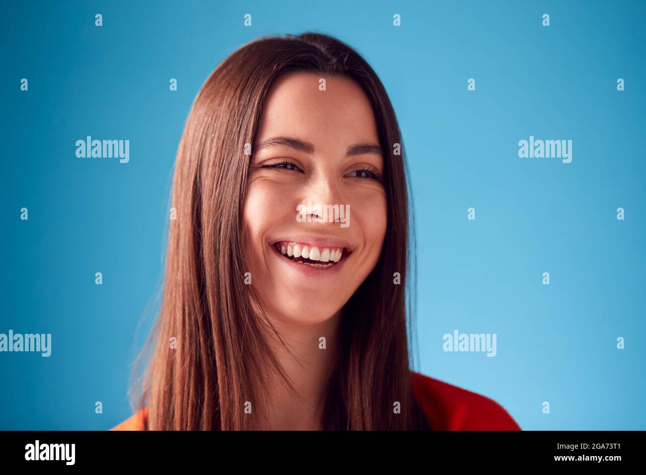 Studio Portrait Of Confident Young Woman Against Blue Background Stock Photo