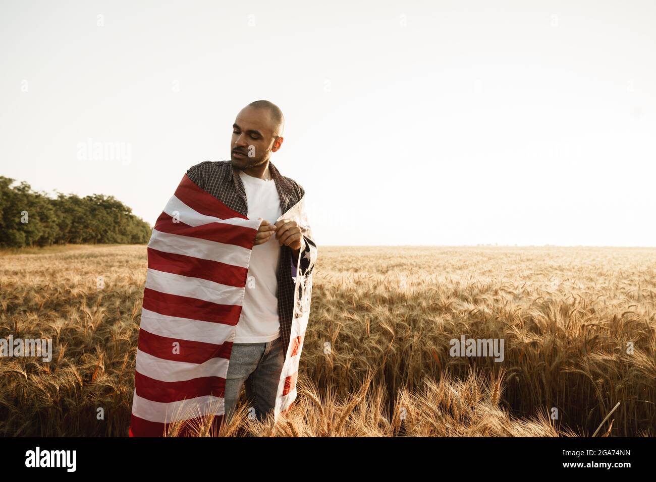 African american young man holding USA national flag through wheat ...