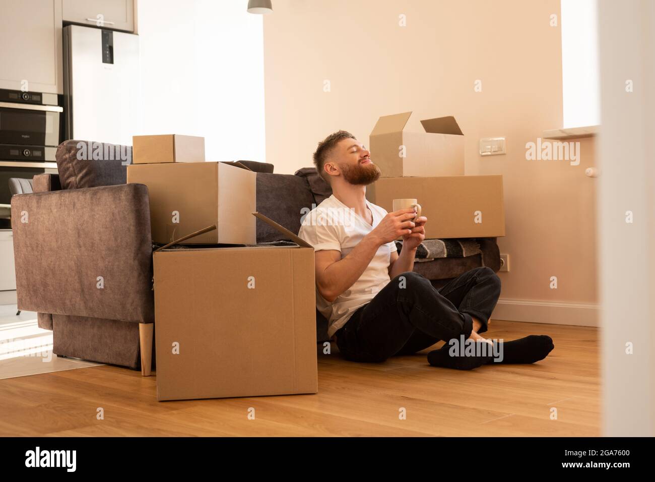 Resting man sitting on floor and drinking tea Stock Photo