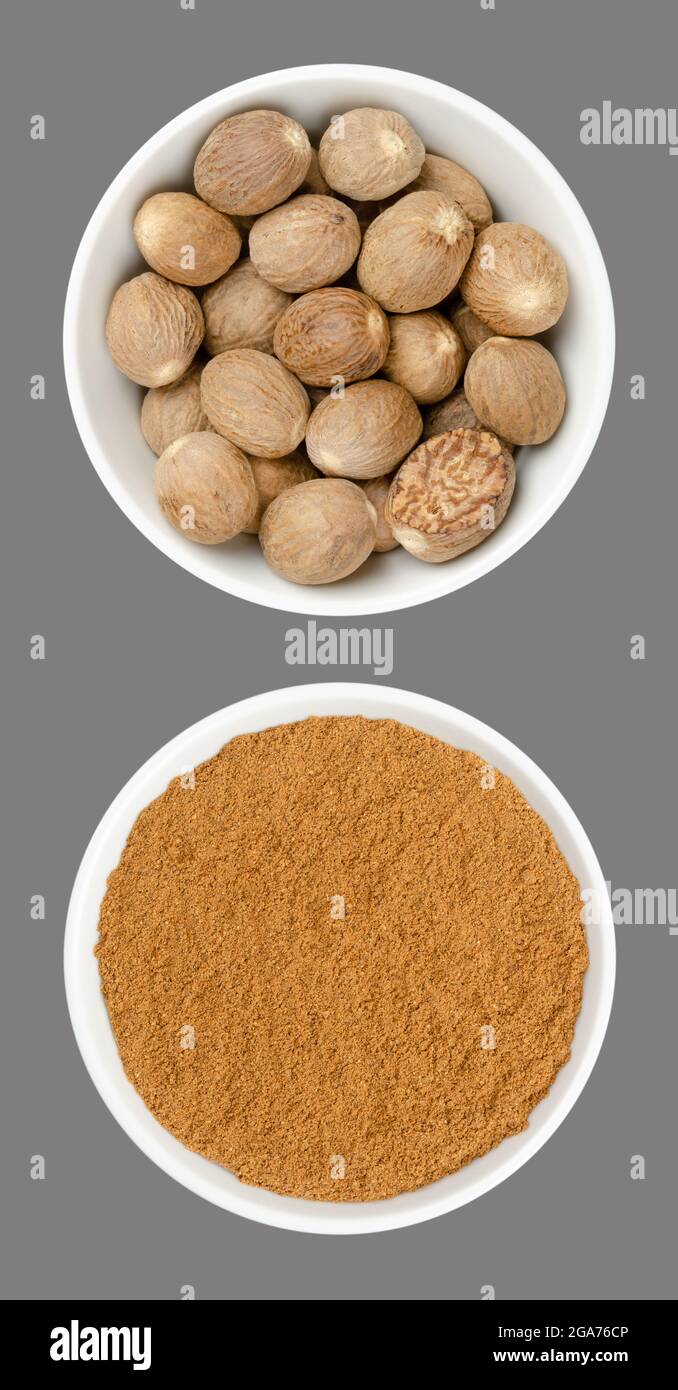 Whole nutmegs and nutmeg powder, in white bowls, on gray background. Fragrant or true nutmeg, dried seeds of Myristica fragrans, a spice. Stock Photo