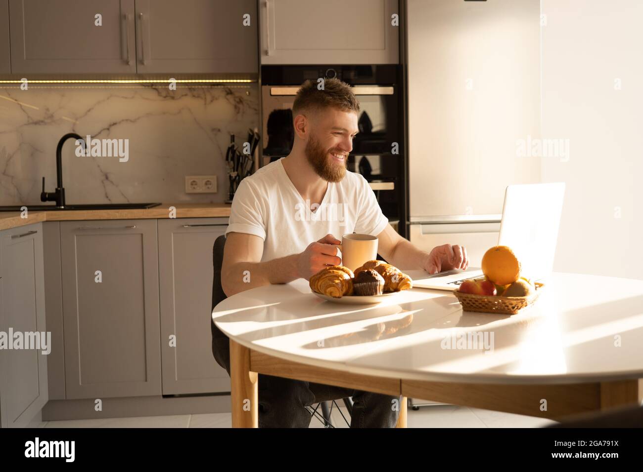 Man using laptop and drinking tea at table Stock Photo