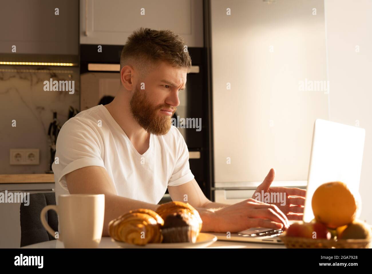 Young tense man using laptop computer at table Stock Photo
