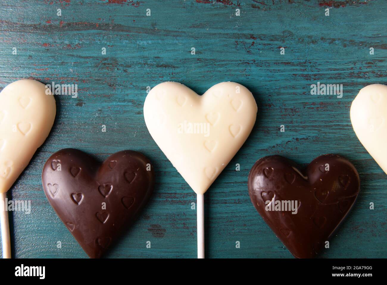 Chocolate heart shaped candies on sticks on wooden background Stock