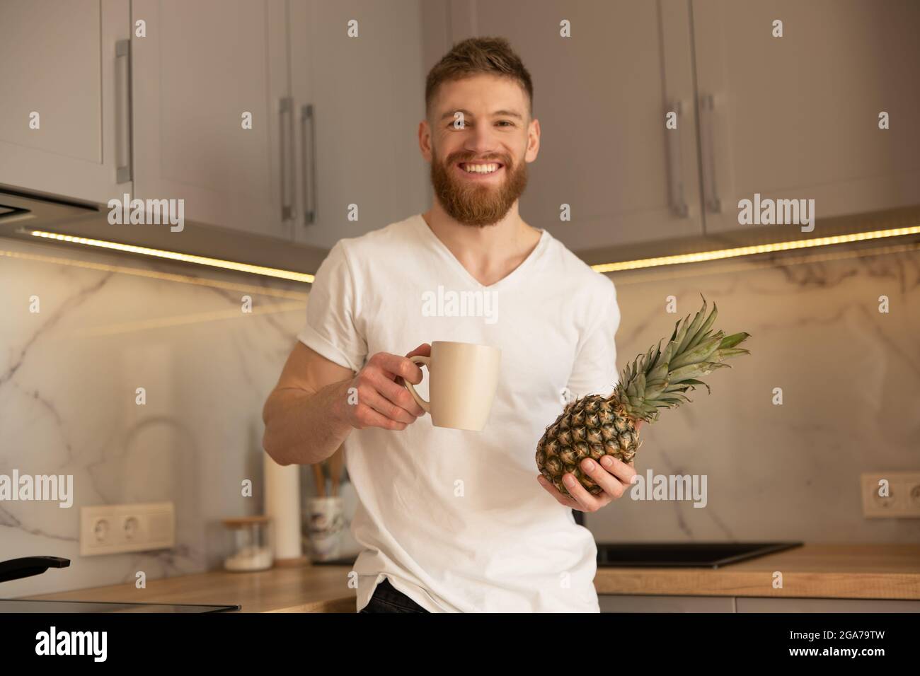 Man drinking tea from cup and holding pineapple Stock Photo