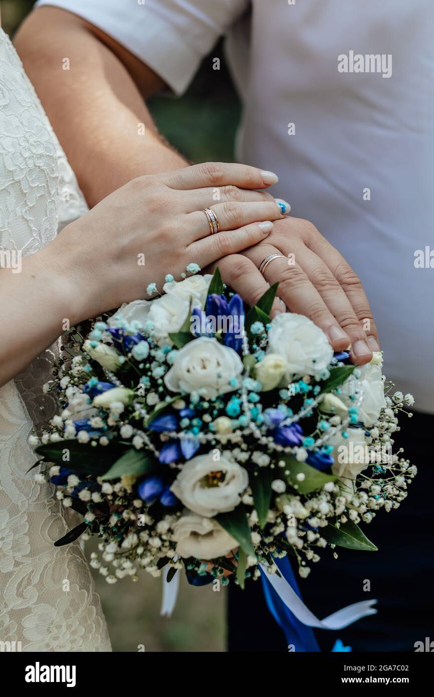 Picture of man and woman with bridal bouquet .Young married couple holding hands, ceremony wedding day. Newly wed couple's hands with wedding rings. Stock Photo