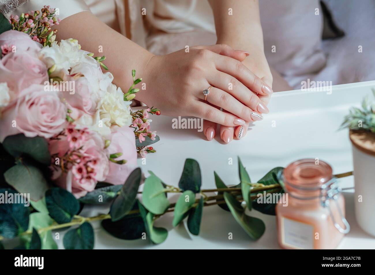Picture of man and woman with bridal bouquet .Young married couple holding hands, ceremony wedding day. Newly wed couple's hands with wedding rings. Stock Photo