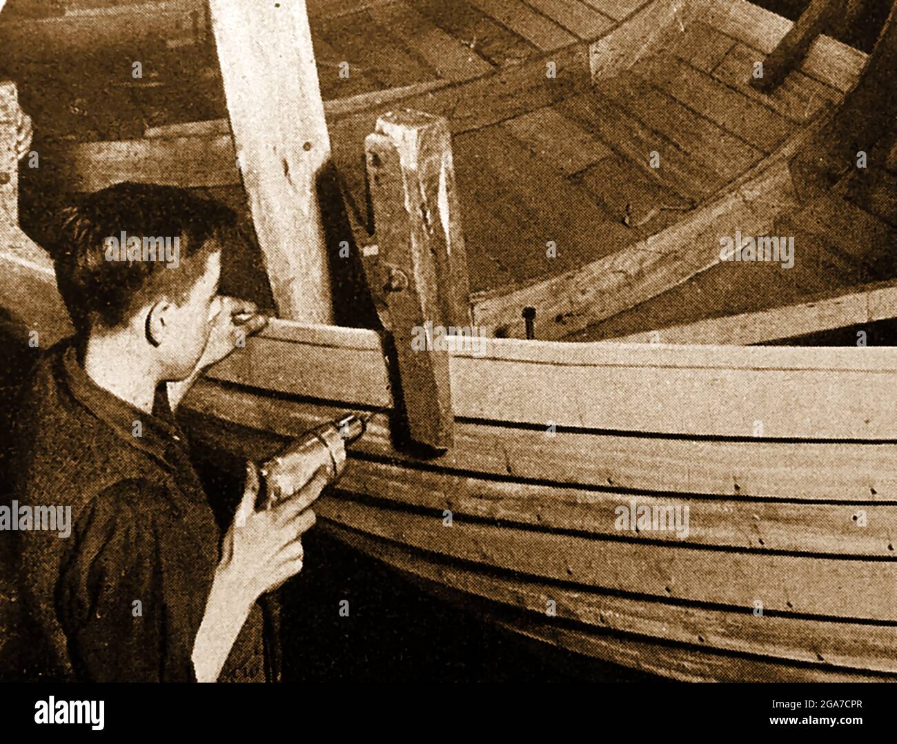 An old printed photograph of a British wooden clinker built lifeboat being riveted Stock Photo