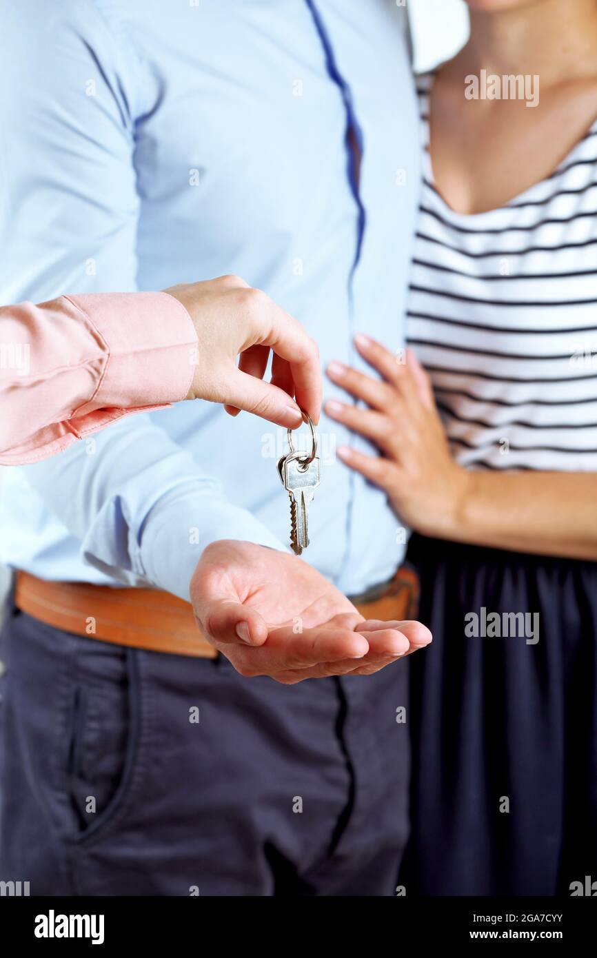 Real estate agent giving keys to young couple Stock Photo - Alamy