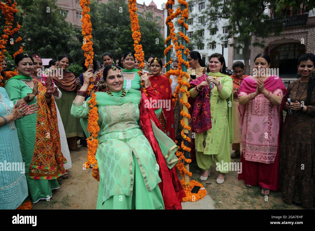 Punjab. 29th July, 2021. A woman rides on a swing and others clap during the Teej festival celebrations in Amritsar district of India's northern state of Punjab, July 29, 2021. The Teej festival is widely celebrated in northern and western India. Credit: Str/Xinhua/Alamy Live News Stock Photo