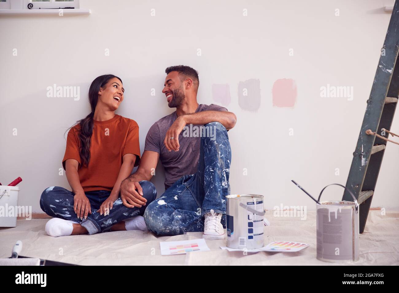 Couple Taking A Break From Painting Test Squares On Wall As They