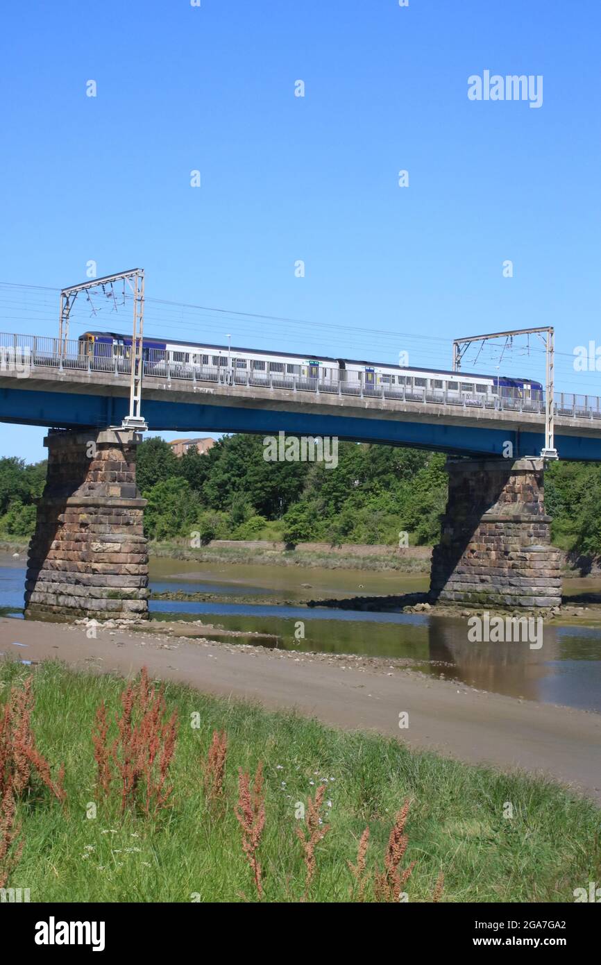 View from St Georges Quay in Lancaster, Lancashire, England to a Northern trains diesel multiple unit crossing Carlisle Bridge on 17th July 2021. Stock Photo