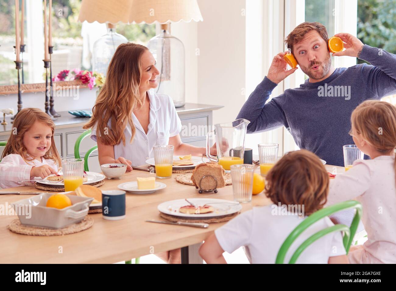 Family Wearing Pyjamas Sitting Around Table Enjoying Pancake Breakfast Together Stock Photo