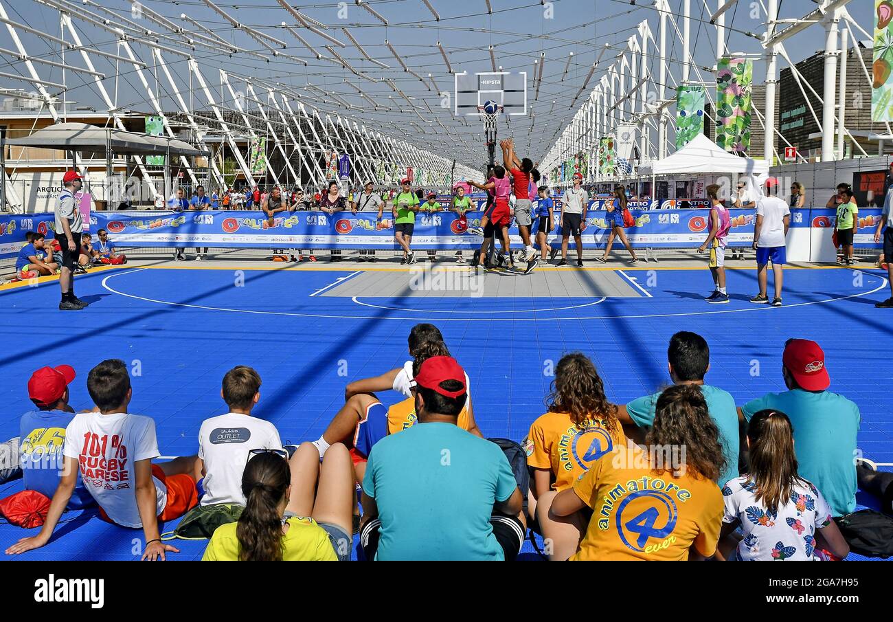 Boys playing on an outdoor basketball court, during a summer camp in