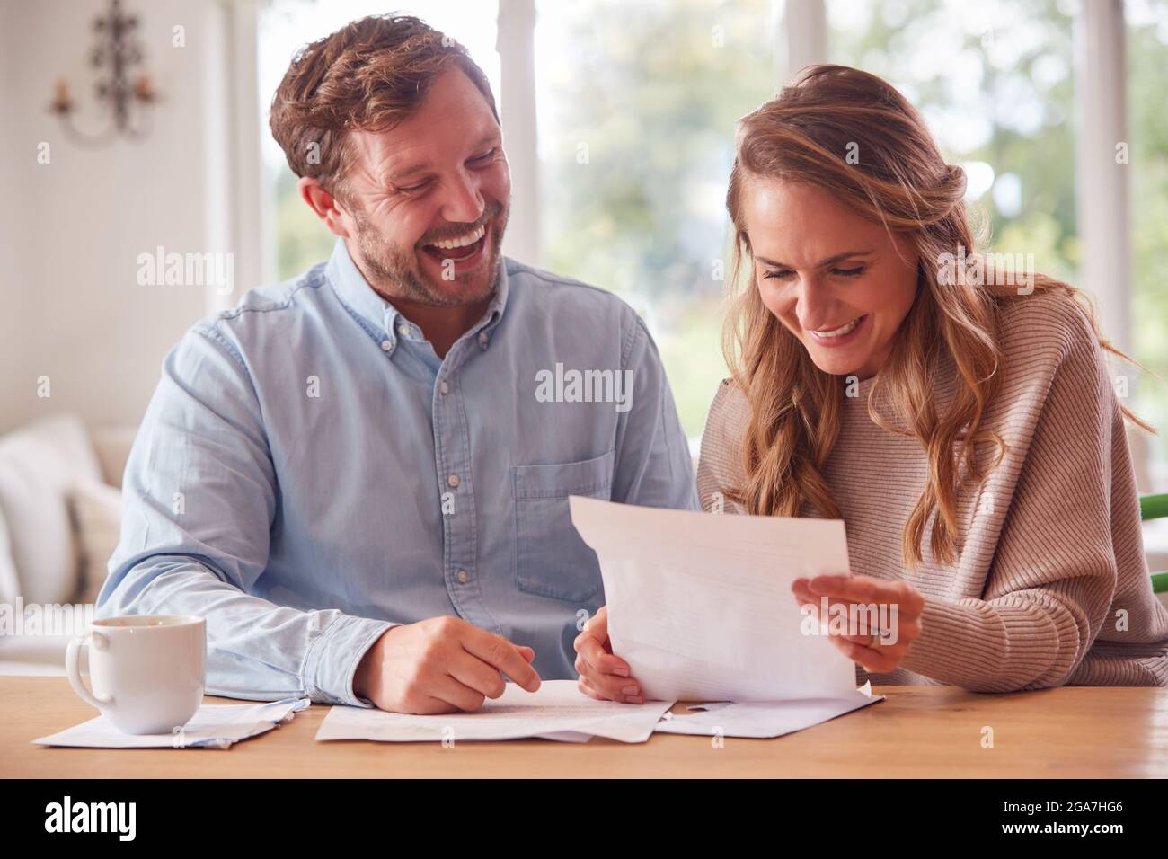 Smiling Couple Sitting At Table At Home Reviewing Domestic Finances Stock Photo