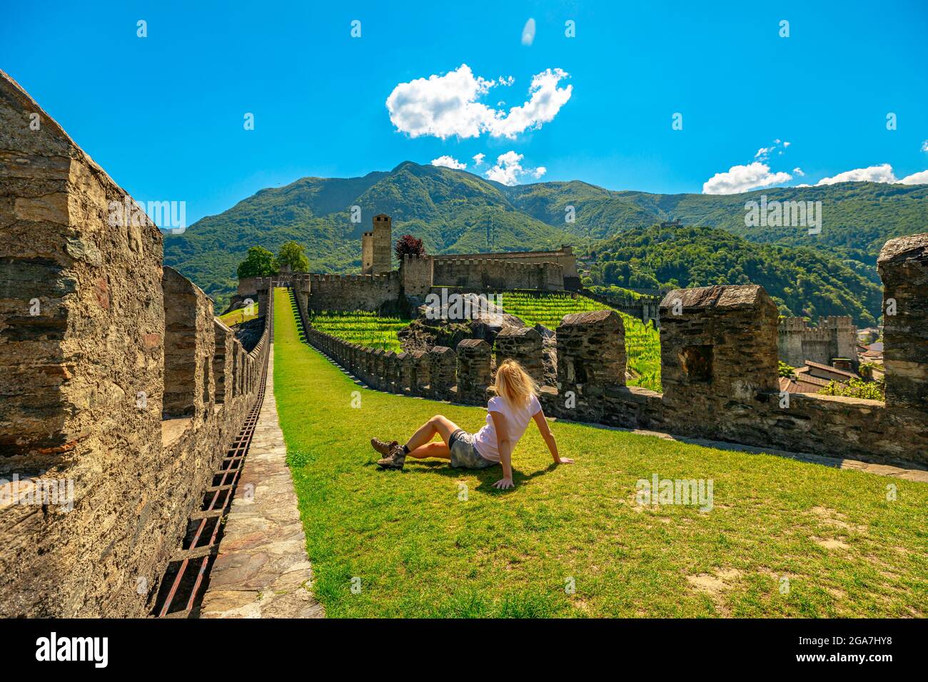 Woman sitting on top of Bellinzona, historic city in Switzerland. Walls of Montebello castle in Bellinzona, capital city of Ticino canton in Stock Photo