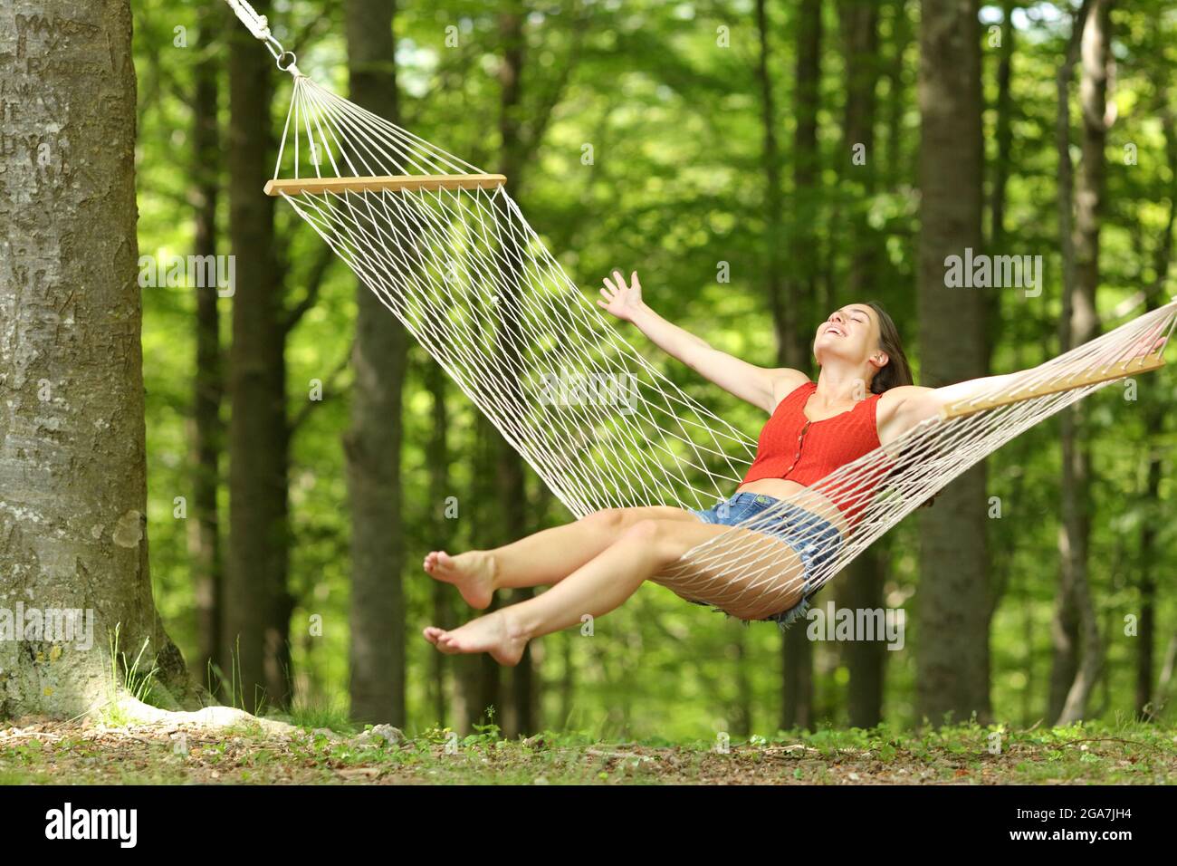 Excited woman swinging on hammock celebrating vacation in a beautiful ...