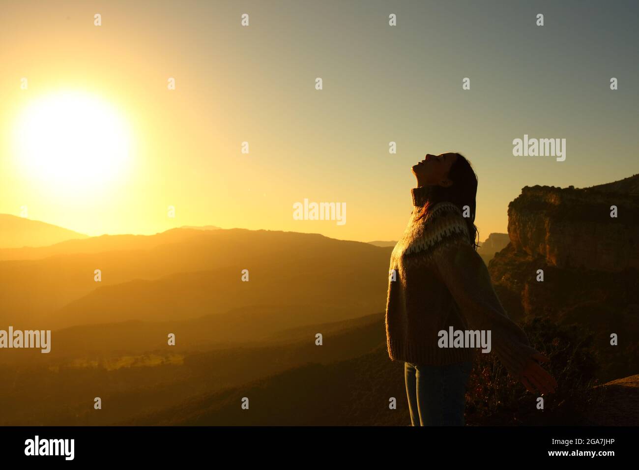 Side view portrait of a backlight silhouette of a woman breathing fresh air in the mountain at sunrise Stock Photo