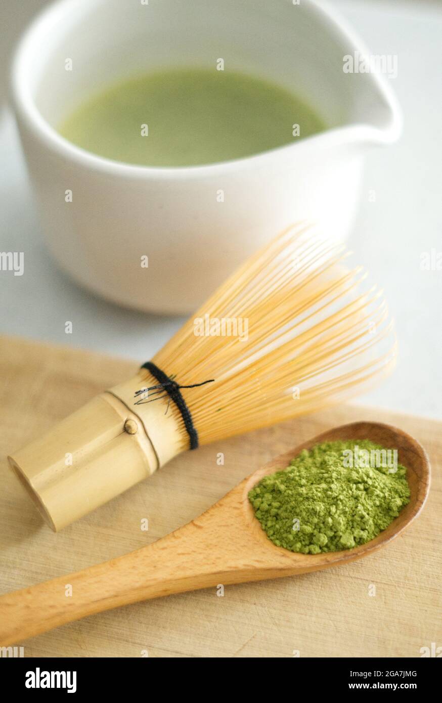 Mixing green Japanese matcha powder in a white ceramic chawan with brown  bamboo wood chasen Stock Photo - Alamy
