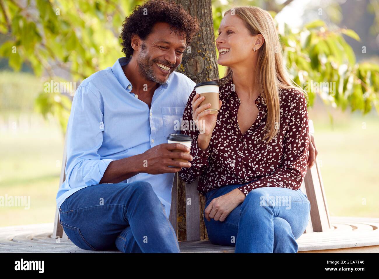 Loving Mature Couple Relaxing Sitting Together On Bench Under Tree In ...