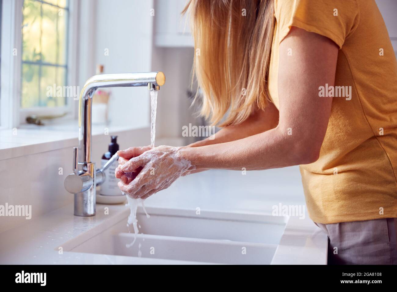 Close Up Of Mature Woman Washing Hands In Kitchen Sink Stock Photo