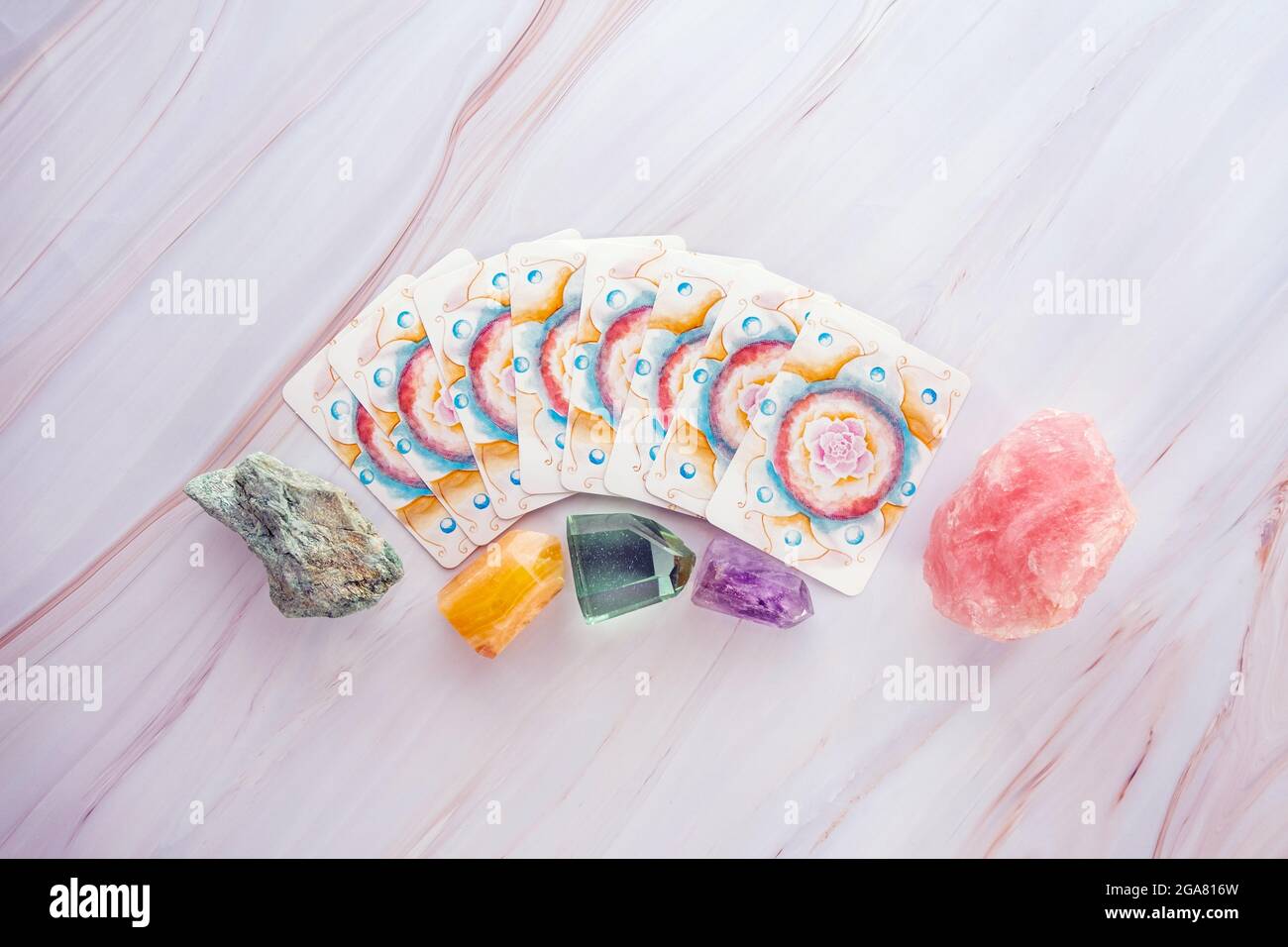 Crystals and gemstones with Tarot cards on a marble table background