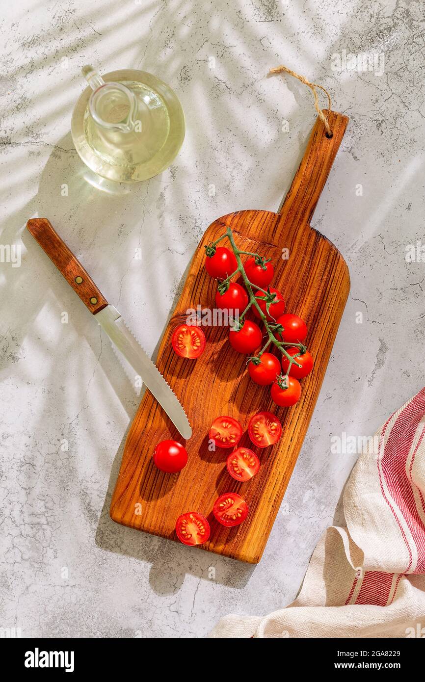 Kitchen board with whole and cut tomatoes. Home cooking concept, top