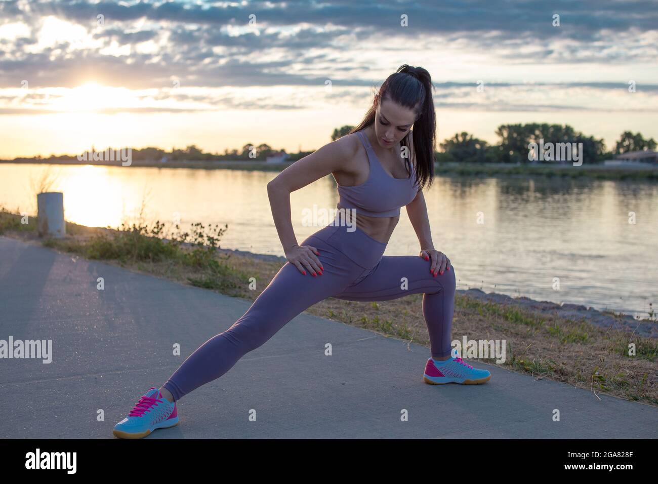 Young Caucasian woman stretching before running, warm up exercise in sunrise Stock Photo