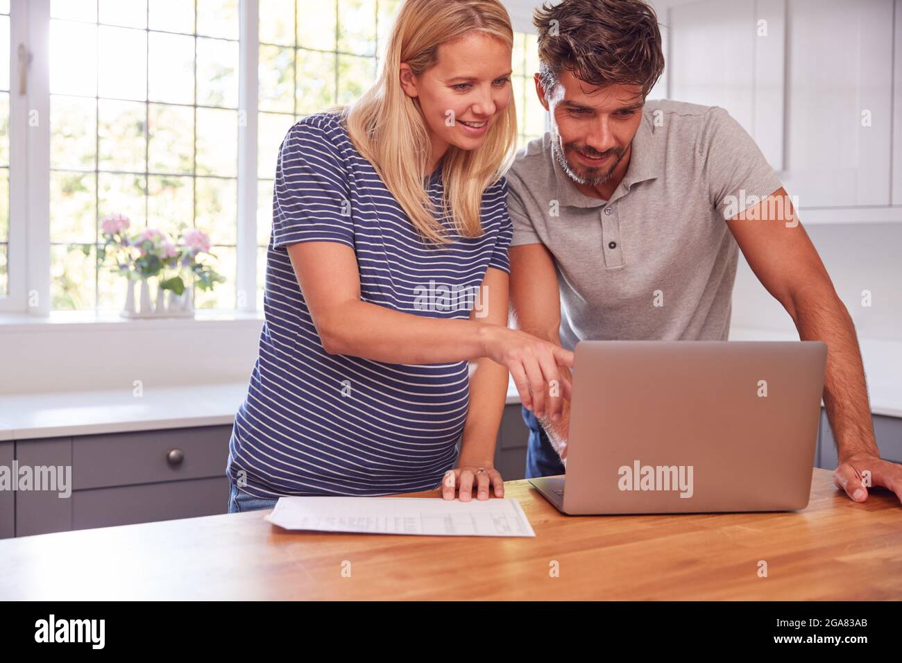 Couple With Pregnant Wife At Home Buying Products Or Services Online Using Laptop Stock Photo
