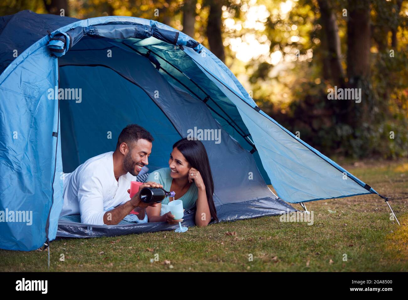 Camping Couple Lying In Tent Drinking Champagne Together Stock Photo - Alamy