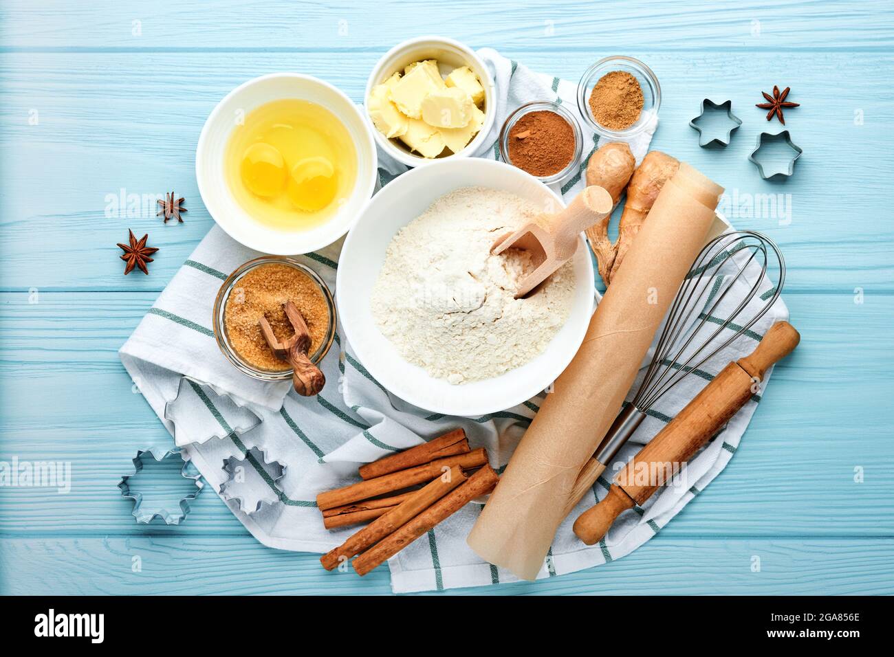 Baking background with ingredients for making gingerbread flour, eggs, kitchen tools, utensils and cookie molds on blue wooden table. Top view. Flat l Stock Photo