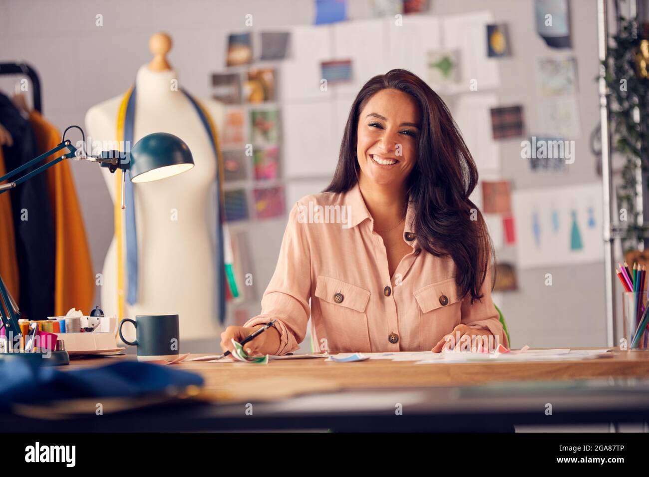 Portrait Of Female Fashion Designer In Studio Working On Sketches And ...