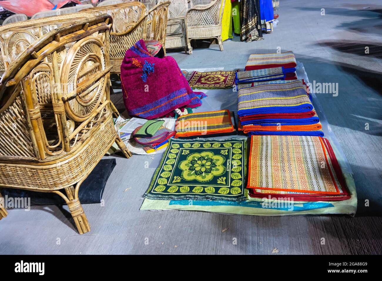 Resting woman seller displaying woolen carpets , door mats, handicraft products. At hastashilpomela or handicrafts fair at Kolkata, West Bengal, India Stock Photo