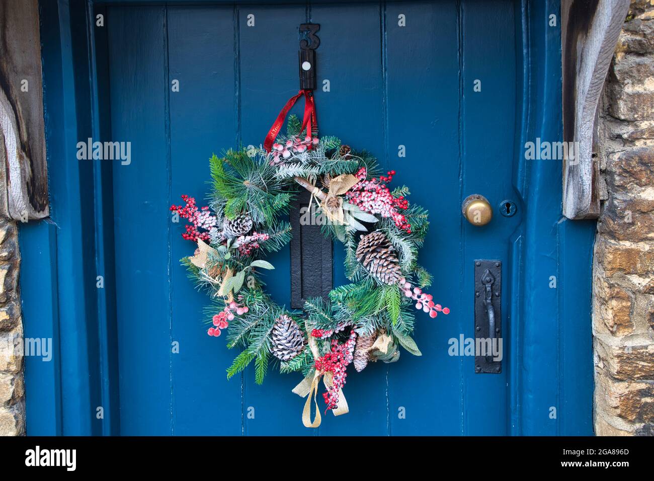 A Christmas wreath hangs from the blue door of a cottage in Lacock village, Wiltshire, England, UK Stock Photo