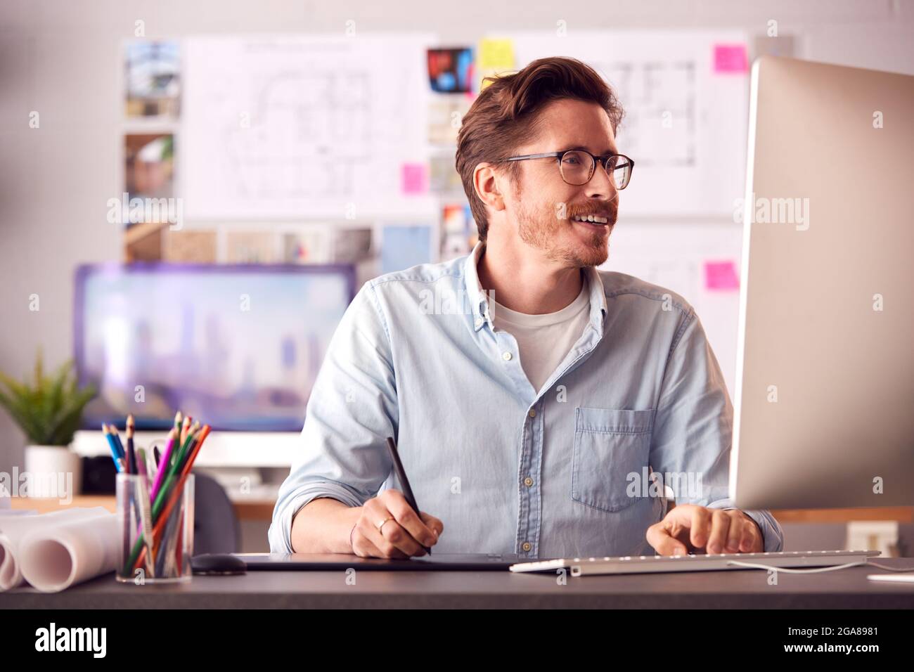 Male Architect In Office Working On Desktop Computer Using Graphics Tablet Stock Photo