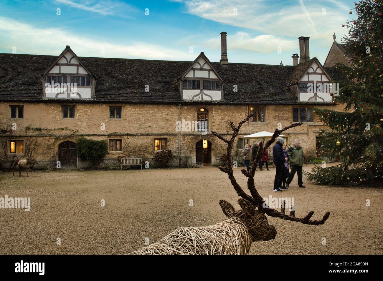 A row of pretty, classic old houses with a large flat area in front. Also a life size reindeer with antlers in the foreground at Lacock, Wiltshire, UK Stock Photo