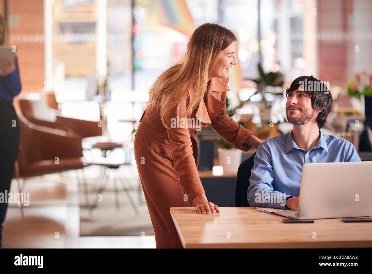 Businessman And Businesswoman Having Informal Meeting By Desk In Modern ...