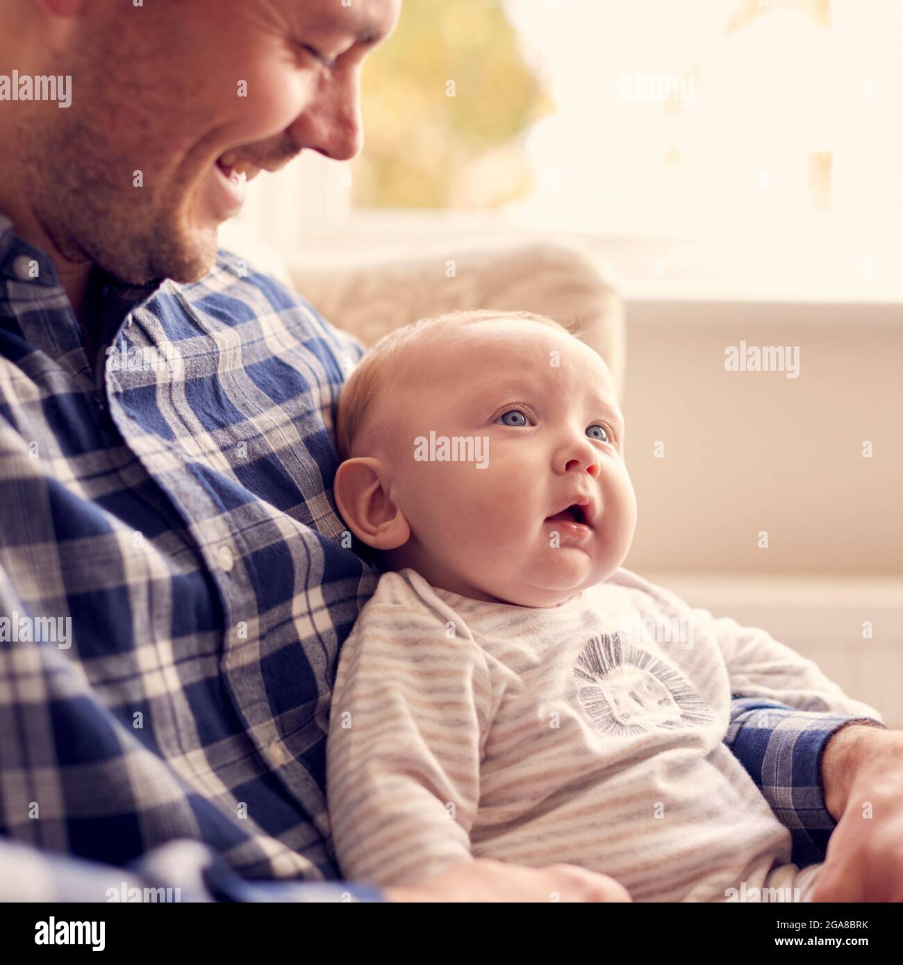 Close Up Of Father Cuddling Baby Son Sitting On Lap In Lounge Chair At Home  Together Stock Photo - Alamy