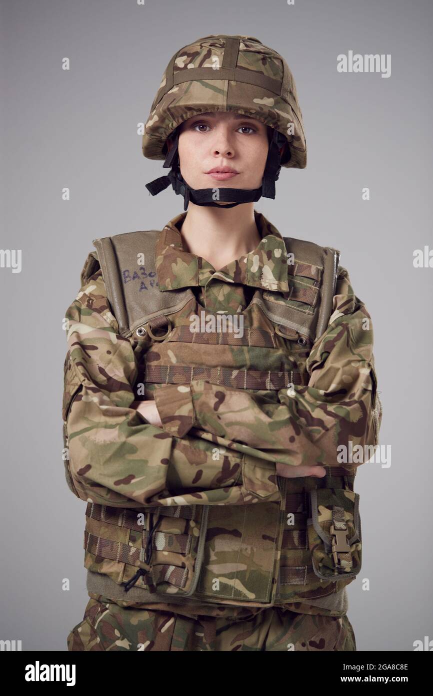 Studio Portrait Of Serious Young Female Soldier In Military Uniform Against Plain Background Stock Photo