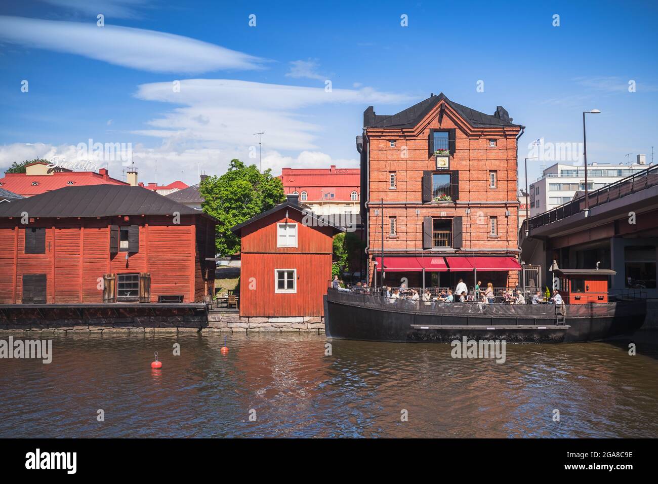 Porvoo, Finland - June 12, 2015: Old red wooden houses on a river coast in historical Finnish town. Ordinary people rest in an outdoor restaraunt terr Stock Photo
