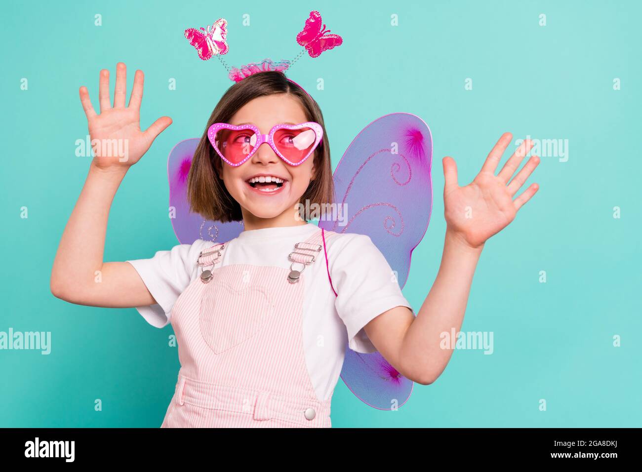 Photo of funny charming schoolgirl dressed pink overall wings dancing looking empty space isolated turquoise color background Stock Photo