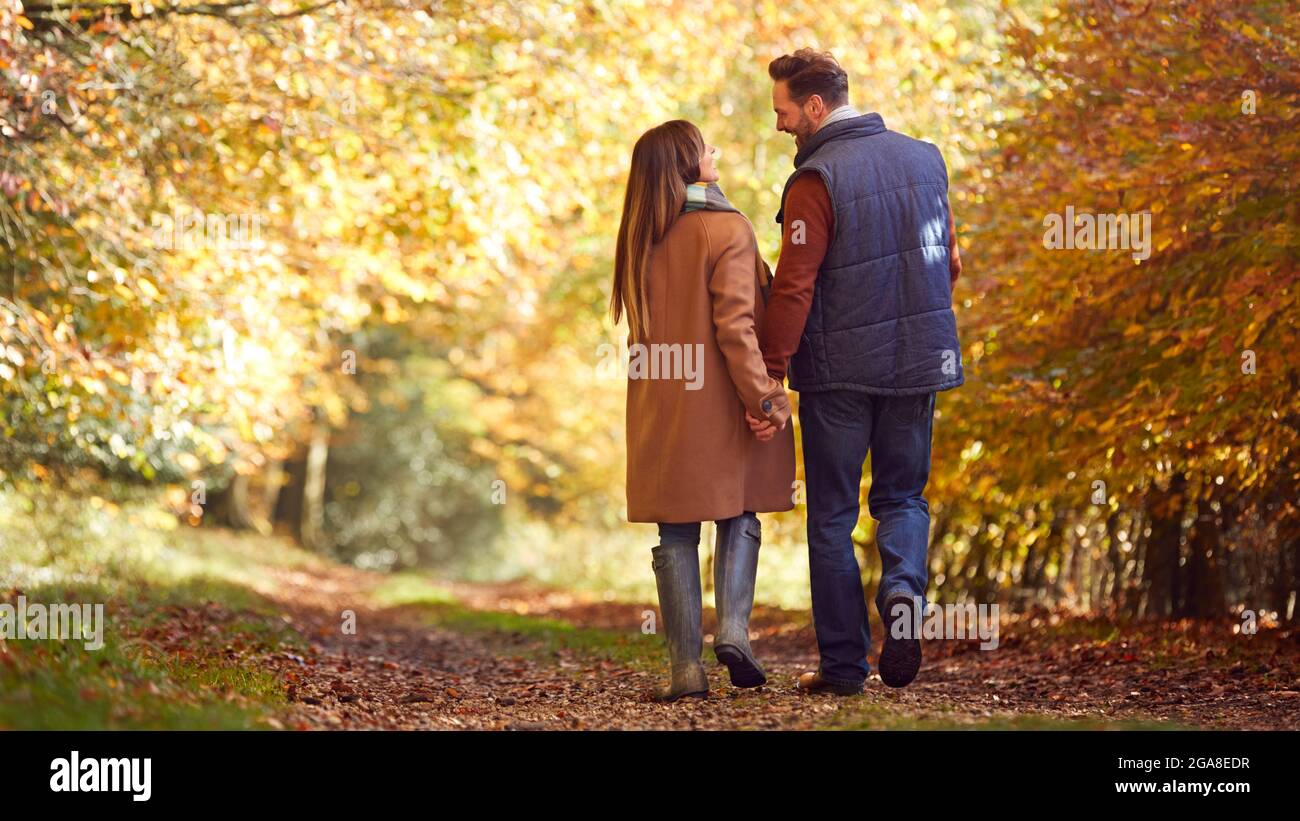 Rear View Of Loving Mature Couple Holding Hands Walking Along Track In ...