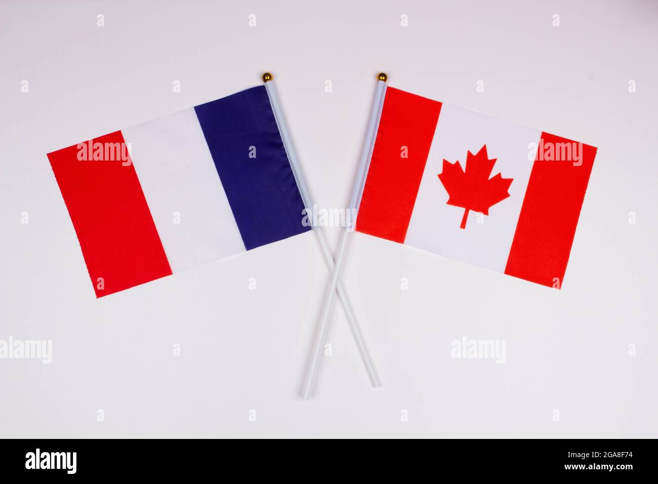 Flag of France and flag of Canada crossed with each other on a white background. Isolated. The image illustrates the relationship between countries Stock Photo
