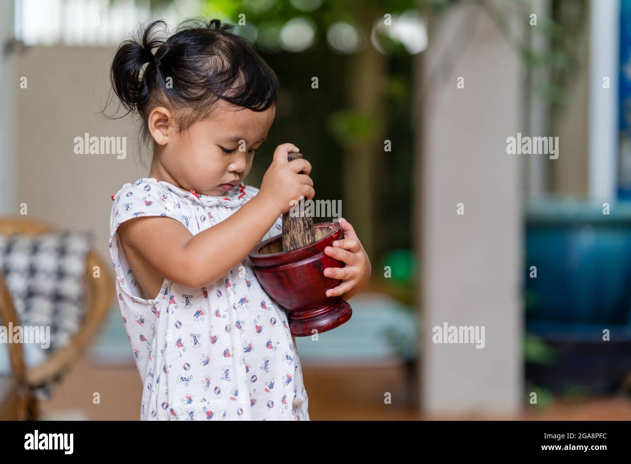 Cute Asian female child using a mortar and pestle Stock Photo Alamy