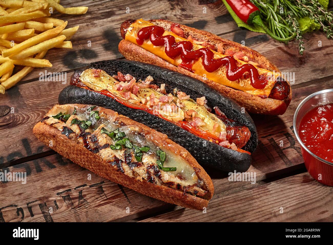 Three hot dogs with various fillings with fries, sauce Stock Photo Alamy