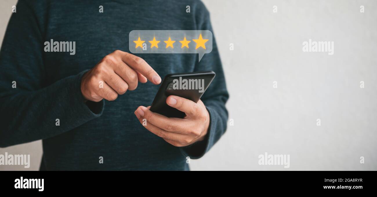 Customer hand  holding smart phone and five star with copy space. Best Excellent Services Rating for Satisfaction.Customer experience satisfaction con Stock Photo