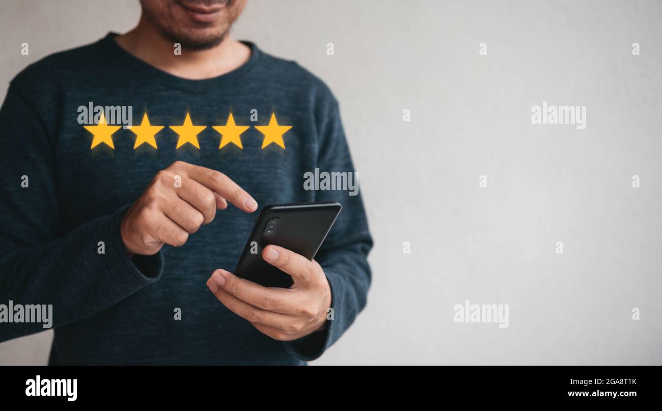 Customer hand  holding smart phone and five star with copy space. Best Excellent Services Rating for Satisfaction.Customer experience satisfaction con Stock Photo