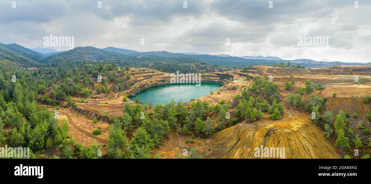 Restoration works in copper mining area with lake in open mine pit and spoil heaps covered with pine trees in Troodos mountains, Cyprus Stock Photo
